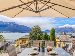 a table with an umbrella on a balcony with mountains at Apartment Onda Blu by Interhome in Gera Lario +31 photos