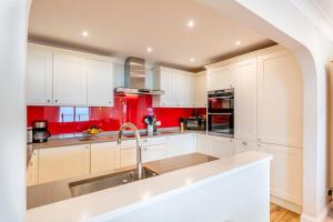 a kitchen with white cabinets and red walls at 3 Bed in Putsborough oc-flt20 in Croyde