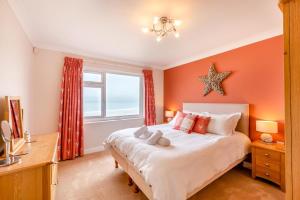 a bedroom with a large bed with an orange wall at 3 Bed in Putsborough oc-flt20 in Croyde +16 photos