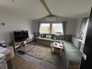 a living room with a couch and a tv at Shivvys at sandylands in Stevenston