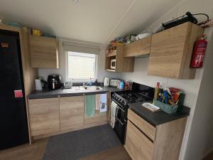 a small kitchen with wooden cabinets and a stove at Shivvys at sandylands in Stevenston