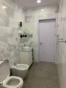 a white bathroom with a toilet and a sink at PP Apartments Deluxe in Năvodari