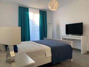 a bedroom with a bed and a flat screen tv at PP Apartments Deluxe in Năvodari