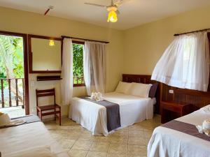 a bedroom with two beds and a window at Pousada Margerie Ubatuba - Ítagua in Ubatuba