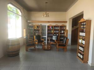 a room with several chairs and a table and shelves of wine bottles at Hotel Avenida in General Alvear