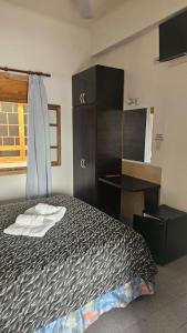 a bedroom with a bed and a desk and a window at Hotel Avenida in General Alvear