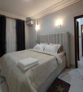 a bedroom with a large bed with white sheets and pillows at Nguem's Appart in Odza I +7 photos