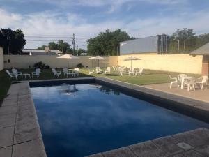 a swimming pool with chairs and tables and umbrellas at Hotel Avenida in General Alvear
