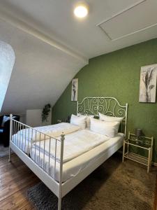 a bedroom with a white bed with a green wall at Gästehaus Flair in Mettlach