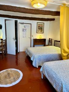 a bedroom with two beds and a table in it at Hôtel Restaurant La Forge in Castellane