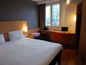 a hotel room with a bed and a desk with a laptop at ibis Aurillac in Aurillac +43 photos