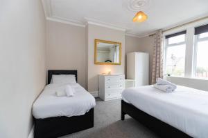 a bedroom with two beds and a mirror at Bright & Comfortable 2-Bed Home 5 mins from Newcastle City Centre - Free Parking in Gateshead