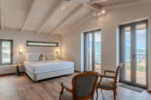 a bedroom with a bed and chairs and windows at Thalassori Villas in Agios Nikolaos