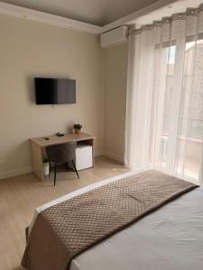 a bedroom with a bed and a desk and a television at Saraceno House G&P in Adrano