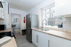 a kitchen with a stainless steel refrigerator and a sink at Bright & Comfortable 2-Bed Home 5 mins from Newcastle City Centre - Free Parking in Gateshead