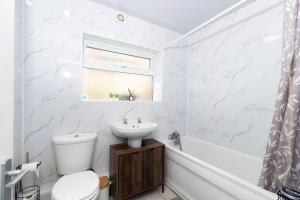 a white bathroom with a toilet and a sink at Bright & Comfortable 2-Bed Home 5 mins from Newcastle City Centre - Free Parking in Gateshead