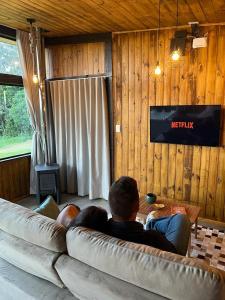 a man sitting on a couch in a living room at Cabanas Monte Belo in Santa Cruz do Sul