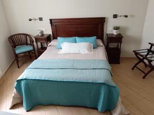 a bedroom with a bed with a blue blanket and two chairs at Alojamiento Playa de Candás in Candás