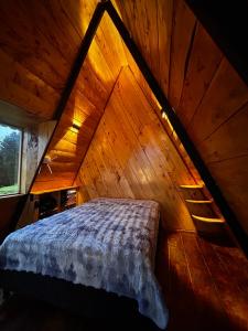 a bed in a room with a wooden ceiling at Chalet - Laguna de la Cocha in Pasto