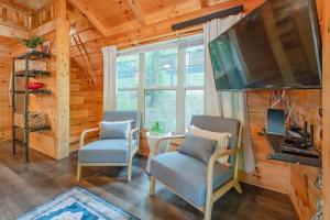 a living room with two chairs and a table and a television at Ani Cabin Tiny Home Bordered By National Forest in Chattanooga