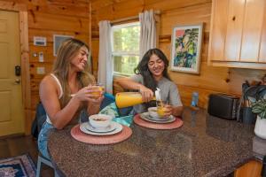 two women sitting at a kitchen counter with drinks at Ani Cabin Tiny Home Bordered By National Forest in Chattanooga