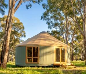 a green yurt in a field with trees at Yurts at Yelverton in Yelverton