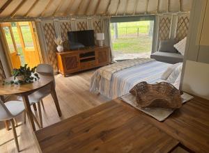 a bedroom with a bed and a tv and a table at Yurts at Yelverton in Yelverton