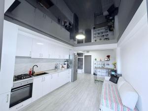 a kitchen with white cabinets and a couch in it at Tower Apartments A6 in Năvodari