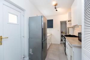 a kitchen with a stainless steel refrigerator in it at Bright & Comfortable 2-Bed Home 5 mins from Newcastle City Centre - Free Parking in Gateshead +6 photos