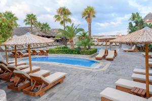 a resort with a pool with lounge chairs and umbrellas at Lavender Villas Chania in Agia Marina Nea Kydonias