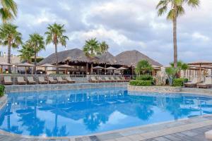 a pool at a resort with palm trees and umbrellas at Lavender Villas Chania in Agia Marina Nea Kydonias
