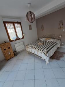 a bedroom with a large bed and a tiled floor at La salicorne in Pendé