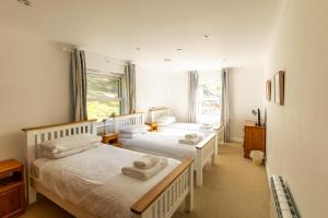two beds in a room with two windows at Beachcombers Apartments in Newquay
