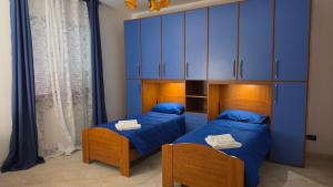 two beds in a room with blue cabinets at La Francigena in Vetralla