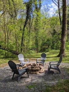 three chairs and a fire pit in a park at Peggers Cabin Luxury Rustic Tiny Cabin Spa in Chattanooga
