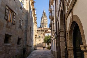 a person walking down an alley with a building in the background at Casa Celsa-Barbantes in Santiago de Compostela