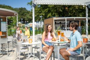 a man and woman sitting at a table with drinks at SUNNY Mobile Homes Bijela Uvala in Poreč