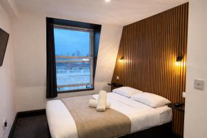 a bedroom with a large bed with a large window at Amsterdam Hotel in London