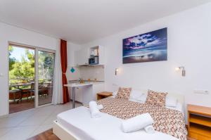 a bedroom with a bed and a kitchen with a table at Apartments Juka in Milna