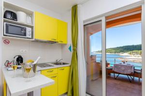 a kitchen with yellow cabinets and a view of the ocean at Apartments Juka in Milna