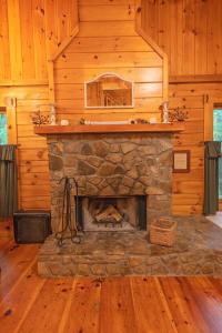 a stone fireplace in a room with wooden walls at Cherokee Ridge Cabin Near The Ocoee River in Ocoee +37 photos