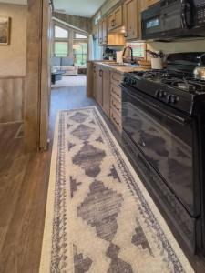 a kitchen with a black stove and a rug at Quail Run Farm- Rustic Tiny Home 3 in Chattanooga +18 photos