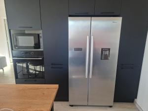 a stainless steel refrigerator in a kitchen next to a stove at Maison Du Bonheur in Erquy