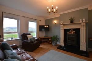 a living room with a fireplace and a chair and a television at An Grianán Getaway in Burt
