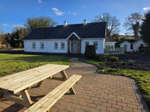 a picnic table in front of a white house at An Grianán Getaway in Burt