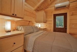 a bedroom with a bed in a wooden cabin at Stefan Cabin Nature-nested Tiny Home Hot Tub in Chattanooga
