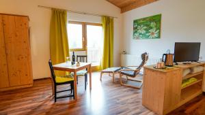 ein Wohnzimmer mit Tisch, Stühlen und Fernseher in der Unterkunft Topfit Leisure Park Freinberg Country Suites und Lodges in Freinberg