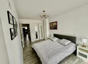 a white bedroom with a bed and a chandelier at Aux Chti Bains in Balaruc-le-Vieux