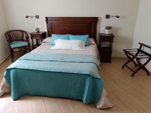 a bedroom with a bed with a blue blanket and two chairs at Alojamiento Playa de Candás in Candás