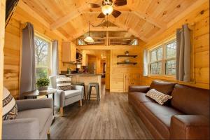 a living room with couches and a kitchen in a log cabin at Meg Cabin Tiny Rustic Comfort On Lookout Mtn in Chattanooga